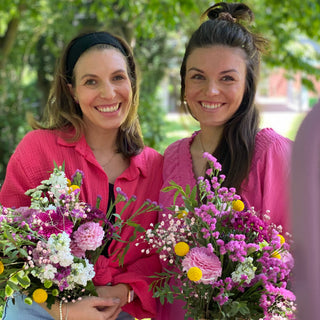 2 Frauen , pink gekleidet, im Gruppenbild mit ihren Werkstücken aus dem Trockenblumen Workshop in Muenster. Beide lächeln in die Kamera und haben ihre gebastelten Blumensträuße in der Hand.