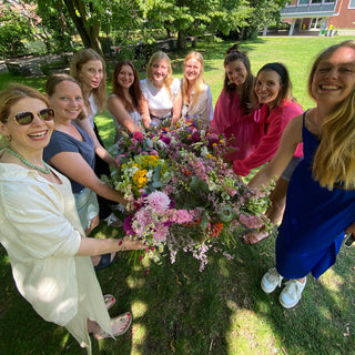 9 Frauen im Gruppenbild mit ihren Werkstücken aus dem Trockenblumen Workshop in Muenster. Alle lächeln in die Kamera und haben ihre selbst gebundenen Blumensträuße in der Hand.