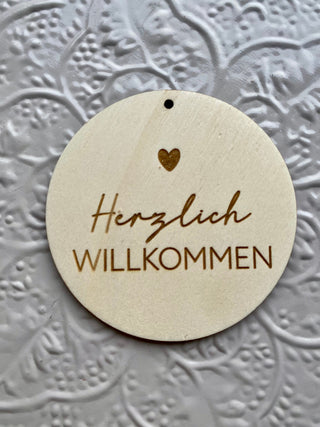 Holz Schild mit der Aufschrift Herzlich Willkommen und einem Herz oben