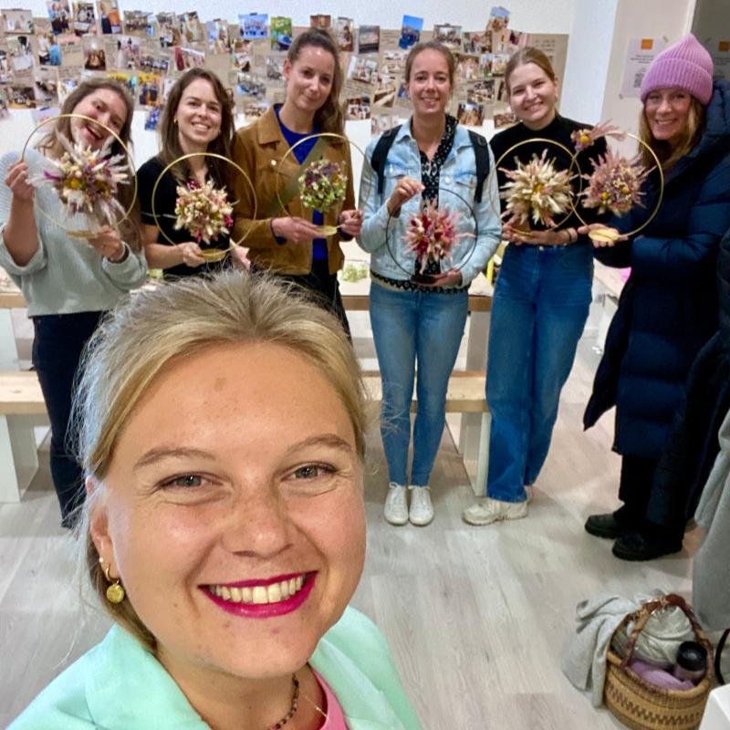 Blumenworkshop Bild vom Teamevent, JGA, Geburtstag - DIY in Münster 
Eine Frauenrunde von 6 Personen hält ihre gebundenen Blumen Werkstück in die Kamera. Vorne steht die grinsende Blumenworkshops Leitung Marleen Jansen, die das Selfie mit der Gruppe gemacht hat. 