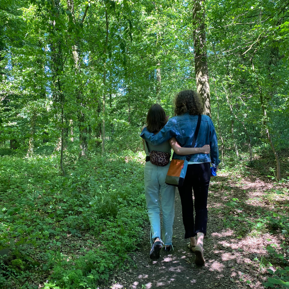 Achtsamkeit beim Waldbaden Münster – zwei Frauen laufen Arm in Arm einen Waldweg entlang.