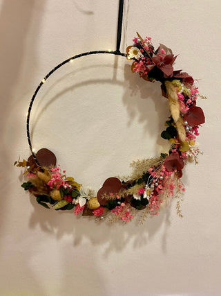 im Blumenworkshop gebastelter Blumenkranz zum Aufhängen - DIY
Version eines schwarzen Blumen-Metallrings, auch Blumenhoop genannt. Die getrockneten Blumen sind zu 2/3 an den Ring gebunden. Oben ist zudem eine Lichterkette angebracht. Das Bild dient zur Ansicht für Blumenworkshop Material oder beispielhaftes Endergebnis.