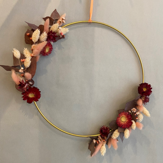 DIY Blumenkranz Workshop – exemplarisches Bild eines im Workshop gebastelten Trockenblumenkranz mit Sommerblumen auf weißem Hintergrund auf dünner, aprikofarbeneder Schnur hängend.