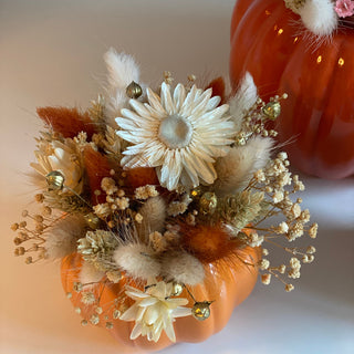 drei Kürbisse sind zu sehen in verschiedenen Orangetönen dekoriert mit gelb, orange, beigen Trockenblumen für einen Workshop im Herbst in Münster. 