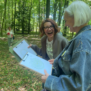 zwei frauen beim Waldbaden workshop in Muenster mit zwei Klemmbrettern von einer entspannenden Übung in der Hand.