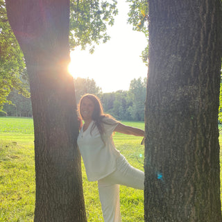 Leni Wiechmann, Yogalehererin
 lächelnd in einer Yoga Pose stehend im Wald zwischen Bäumen mit Sonne in Münster für den Workshop Waldbaden meets Yoga.